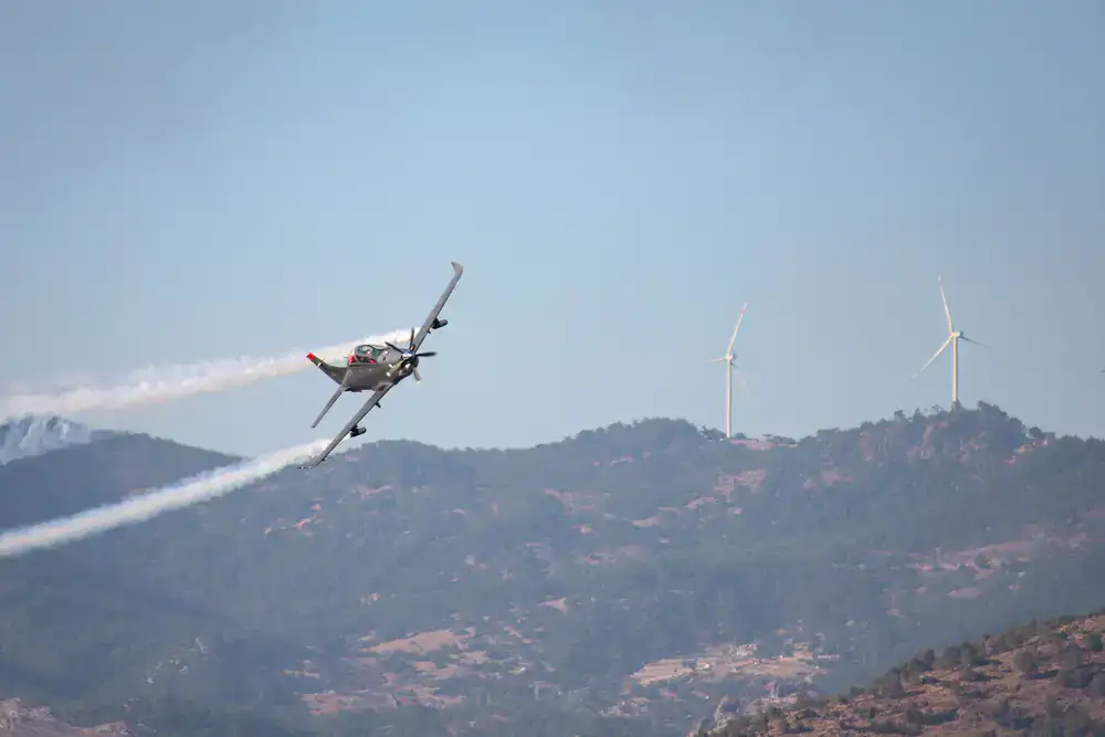 Small agile stunt plane banking sharply near mountains